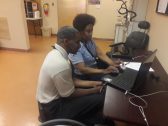 A man in a wheelchair and a woman use a laptop computer together