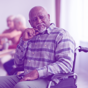 An older black man seated in a wheelchair looks pensively to the side