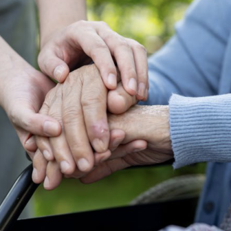 Young hands holding an older person's hands