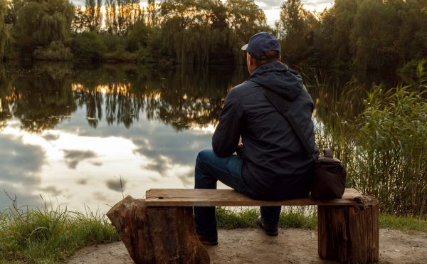 A man sitting alone in front of a lake